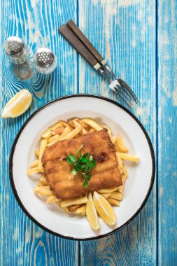 Tabakta patates kızartması olan kızarmış morina balığı. Üst görünüm.