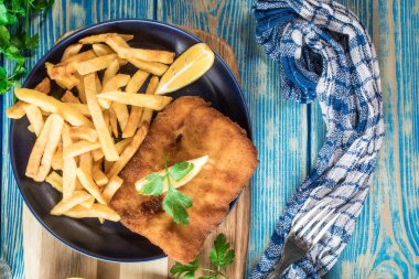 Tabakta patates kızartması olan kızarmış morina balığı. Üst görünüm.