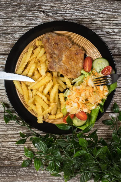 Geleneksel Polonya yemeği: kızarmış domuz pirzolası, patates kızartması ve salata ile servis edilir..