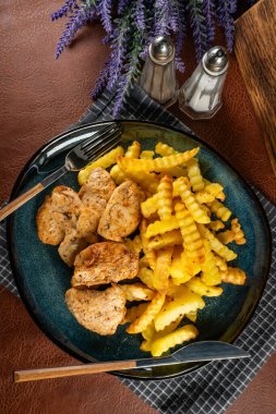 Kızarmış patates ve fırında tavuk parçaları.