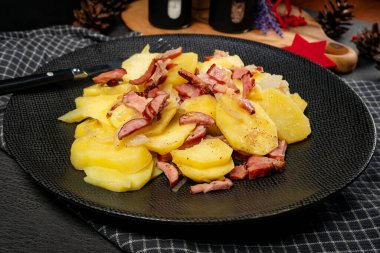 Tütsülenmiş domuz pastırması, sosis ve soğanlı haşlanmış patates. Geleneksel bir cilası..