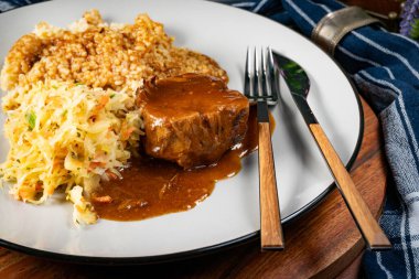 Sos soslu domuz budu, arpa ve lahana turşusu salatası. Sığ alan derinliği.