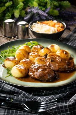 Geleneksel Alman haşlanmış domuz yanakları kahverengi soslu ve mantarlı Silezya köftesi ile servis ediliyor..