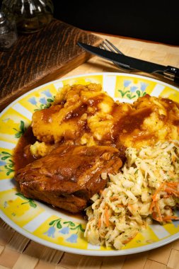 Patates püresi ve salatayla servis edilen acılı soslu domuz pirzolası. Sığ alan derinliği.