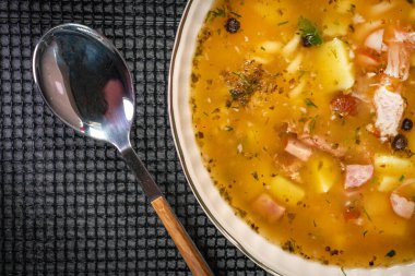 Beyaz sosis, patates ve küçük hamur köfteleriyle bezelye çorbası. Yüzeyin derinliği. Koyu ışık.