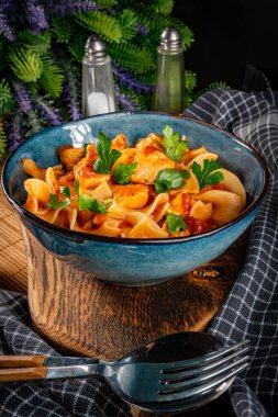 Domates soslu erişteli tavuk parçaları. Sığ alan derinliği.