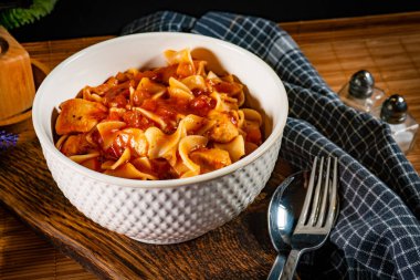 Domates soslu erişteli tavuk parçaları. Sığ alan derinliği.