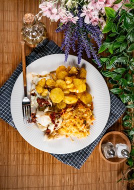 Fırınlanmış morina parçaları, mozarella peyniri ve fırında patatesle servis edilen kurutulmuş domates..
