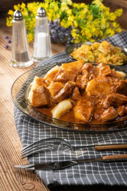 Soslu sığır eti yahnisi, patates köftesiyle servis edilir..