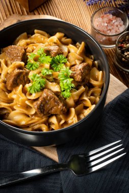 Tahta masada biftek soslu Tagliatelle yosunları. Koyu ışık.