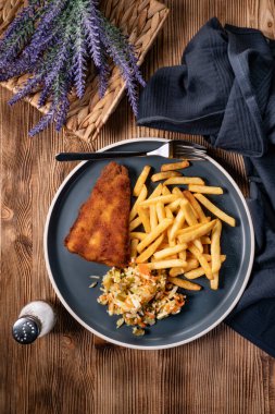 Kızarmış balık fileto, patates kızartması ve mavi tabakta salata. Üst görünüm.