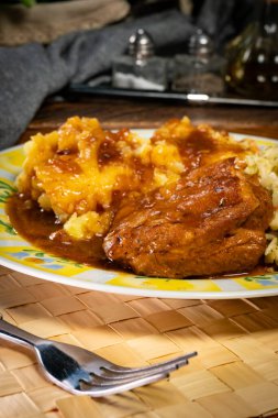 Patates püresi ve salatayla servis edilen acılı soslu domuz pirzolası. Sığ alan derinliği.