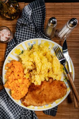 Kızarmış tavuk göğsü fileto haşlanmış patates ve havuç salatası ile servis edilir..