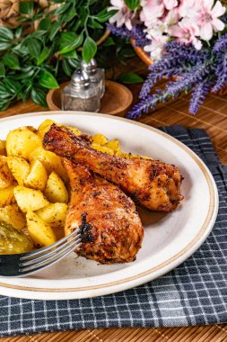 Fırında tavuk budu ve patates. Sığ alan derinliği.