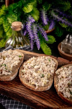 Tahta bir tahtanın üzerinde ton balıklı sandviç ve yumurta. Sığ alan derinliği.