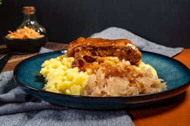 Patates püresi ve lahana turşusuyla servis edilen baharatlı soslu domuz pirzolası. Sığ alan derinliği.