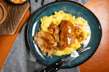 Patates püresi ve lahana turşusuyla servis edilen baharatlı soslu domuz pirzolası. Sığ alan derinliği.