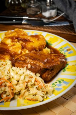 Patates püresi ve salatayla servis edilen acılı soslu domuz pirzolası. Sığ alan derinliği.