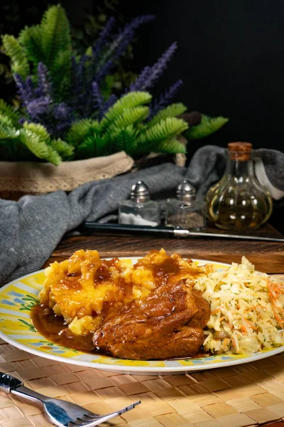 Patates püresi ve salatayla servis edilen acılı soslu domuz pirzolası. Sığ alan derinliği.