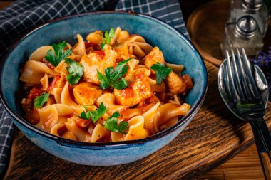 Domates soslu erişteli tavuk parçaları. Sığ alan derinliği.