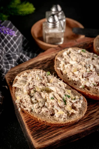 Tahta bir tahtanın üzerinde ton balıklı sandviç ve yumurta. Sığ alan derinliği.