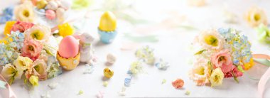 Renkli yumurtalar, şekerler ve çiçek dolu Paskalya arkaplanınız kutlu olsun. Tatil için masa dekorasyonu.