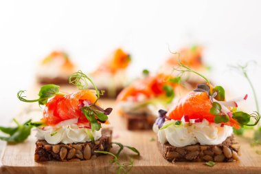 Füme somonlu mini kanepeler, yumuşak peynir ve parti için glütensiz tohum ekmeği üzerine taze sebzeler..