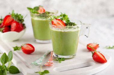 Hindistan cevizi sütüyle kaplı yeşil çay panna cotta ve bardakta çilek. Yaz için sağlıklı glütensiz tatlı kavramı.