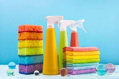 Mavi arkaplanı temizlemek için renkli malzemeler. Deterjan şişeleri, süngerler ve paçavra renkleri. Bahar temizliği konsepti.