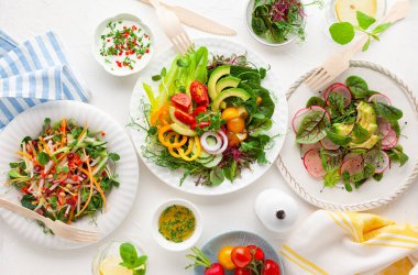 Çeşitli sağlıklı salatalar taze sebzeler, meyveler ve mikro sebzeler masada. Temiz yemek, yemek kasesi. Üst Manzara. Ev yemeği kavramı.