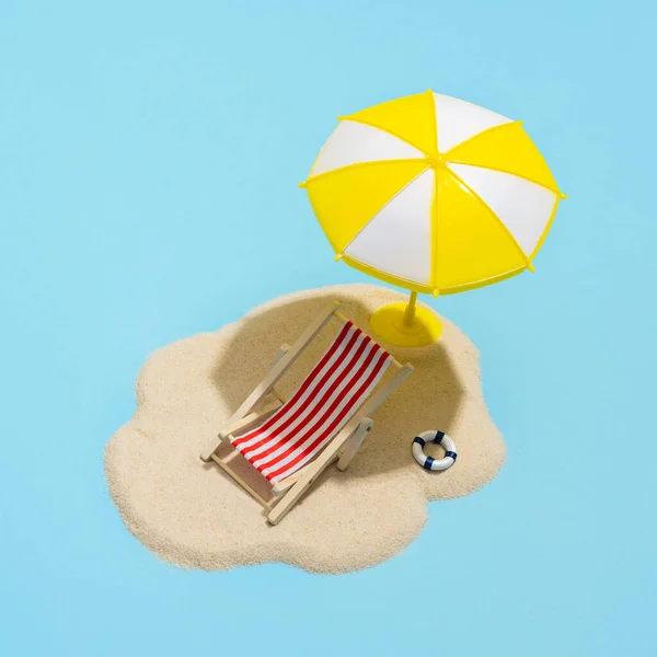 Summer concept. Sun umbrella and sun lounger on sea sand on blue background. Sun protection concept in summer.