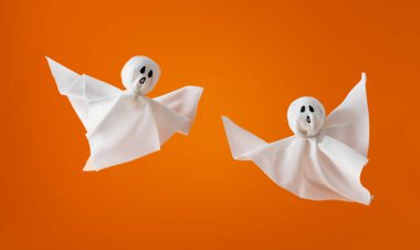 Turuncu arka planda Cadılar Bayramı hayaletleri. Cadılar bayramı konseptin kutlu olsun. Festival partisi için el yapımı dekorasyon.