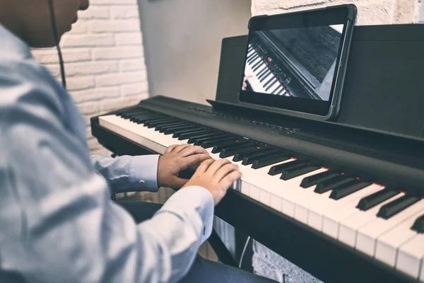 Child learning piano online lessons in quarantine . Coronavirus life style