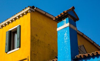Burano, Venedik 'te mavi bacalı, mavi gökyüzü olan renkli sarı bir ev.