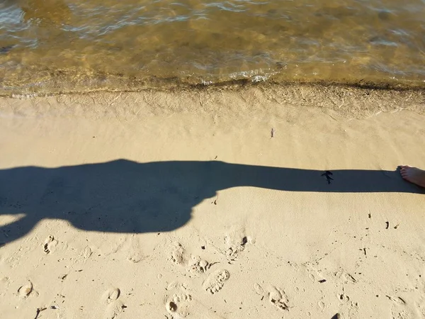Sombra de pessoa em areia de praia com água — Fotografia de Stock
