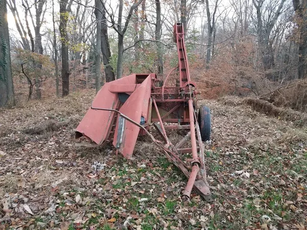 Oude rode metalen machine met bladeren en bomen — Stockfoto