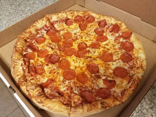 Biberli pizza tezgahın üstünde karton kutuda.