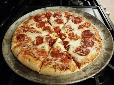 Fırında metal tepside peynirli dilimlenmiş pepperoni pizza.