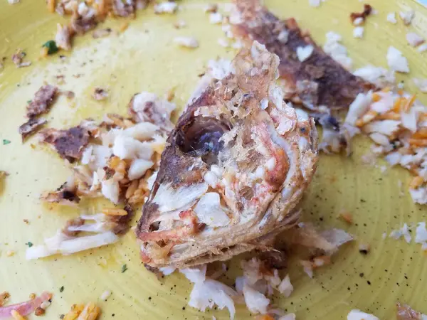 Gebratener Fischkopf auf gelbem Teller gegessen — Stockfoto