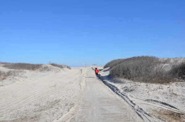Niño en abrigo rojo corriendo en camino de arena en la playa —  Fotos de Stock