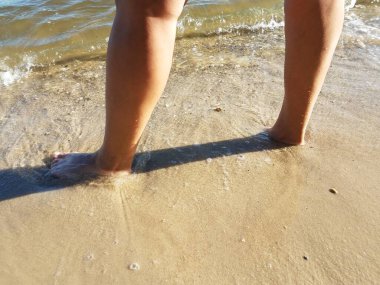 Kadınlar kumsalda ıslak kumda ayakta dururlar.