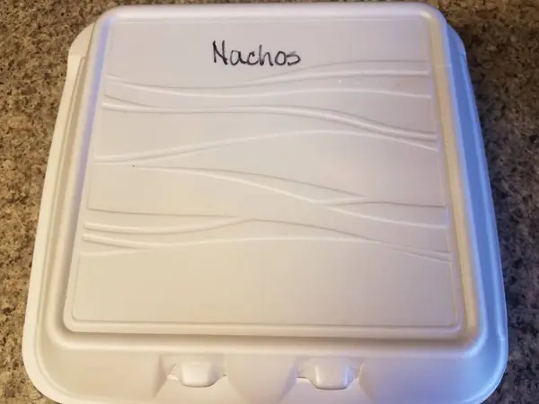 Beyaz köpüklü cips konteynırında nacho yazıyor. — Stok fotoğraf