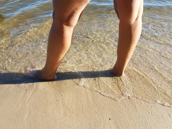Pies de las mujeres de pie en la arena mojada en la playa —  Fotos de Stock