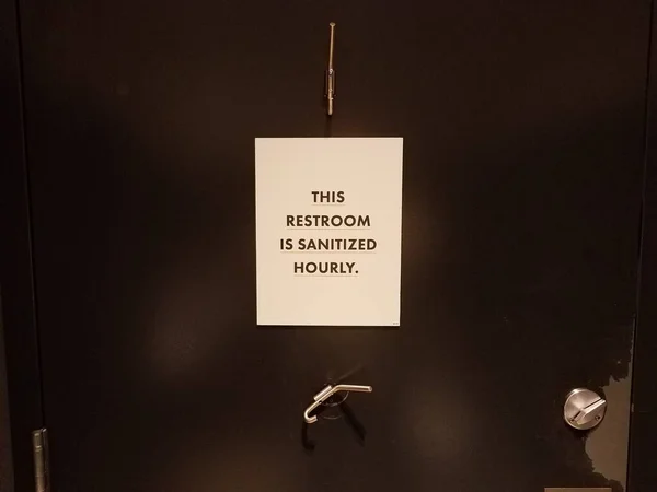 Baño es santized signo por hora en la puerta del baño — Foto de Stock