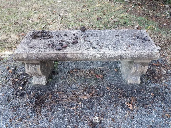 Špinavá betonová lavička nebo sedačka se štěrkem a trávou — Stock fotografie