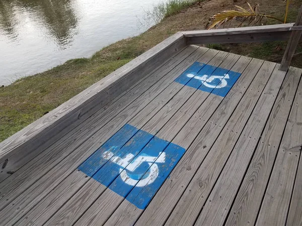 Blaue Rollstuhllogos auf Holzpromenade in Flussnähe — Stockfoto