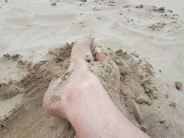 Pies y dedos de los pies masculinos en arena en la playa — Foto de Stock