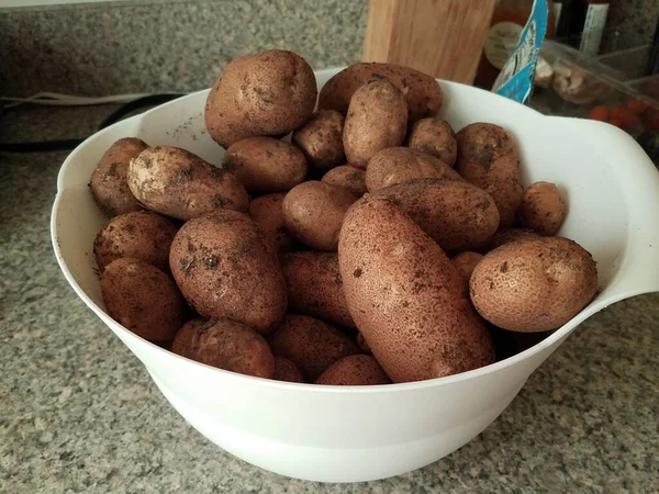 Witte schaal gevuld met vuile aardappelen op de toonbank — Stockfoto