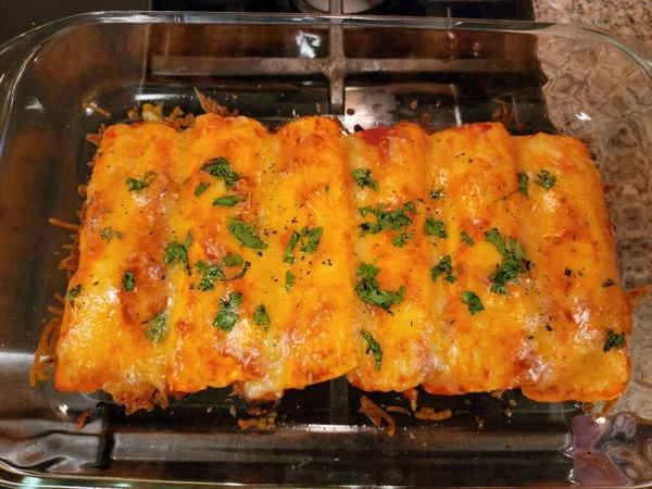 Enchiladas quentes cheesy no recipiente de vidro no fogão — Fotografia de Stock