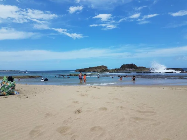 波多黎各伊莎贝拉的海滩，沙滩上有沙子，还有人在水里 — 图库照片